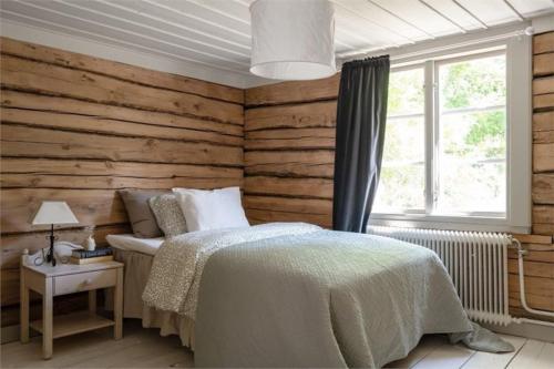 um quarto com paredes de madeira, uma cama e uma janela em Prästgården i lantlig miljö med fyra sovrum, dusch, kök och vardagsrum em Knivsta
