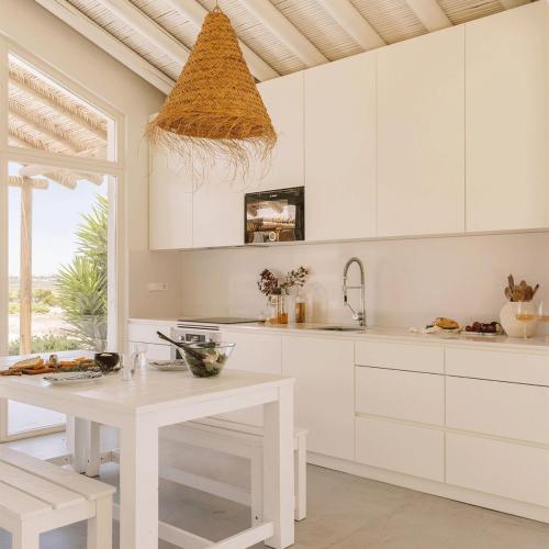a white kitchen with white cabinets and a table at Flor de Arroz in Carvalhal