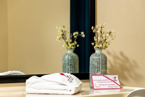 two vases with flowers on a table in front of a mirror at HOTEL DEL VALLE INN IXMIQUILPAN in Ixmiquilpan