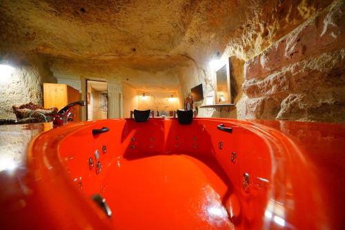 an orange bath tub in a room with a stone wall at Cappadocia Nar Cave House & Swimming Pool in Nevsehir
