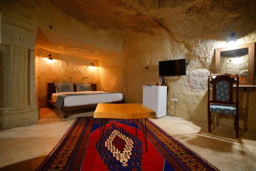 a room with a bed and a table and a rug at Cappadocia Nar Cave House & Swimming Pool in Nevsehir