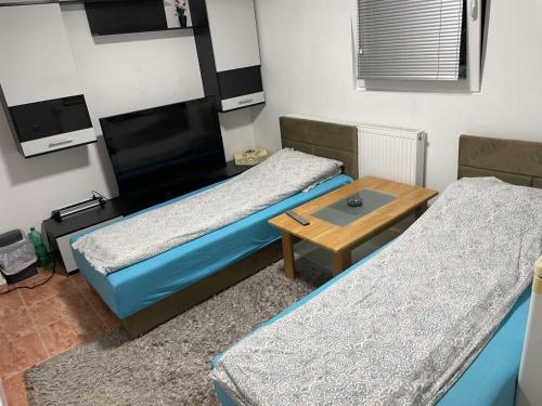 a room with two beds and a table and a tv at APARTMAN SARAJEVO DVOKREVETNI-dvije osobe in Sarajevo