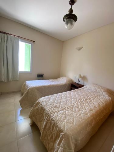 a bedroom with two beds and a window at Loma Maria in Puerto Madryn
