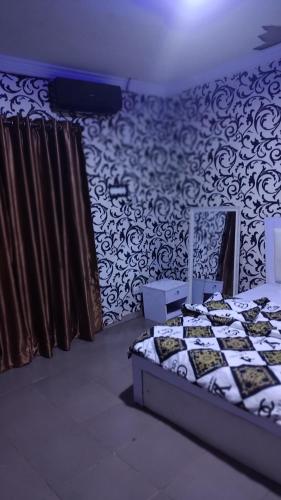 ein Schlafzimmer mit einem Bett in einem Zimmer mit einer Tapete in der Unterkunft White Emirates Hotel and Apartment in Lagos