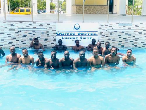 a group of men posing in a swimming pool at odivin hotel luxury suite in Gonaïves