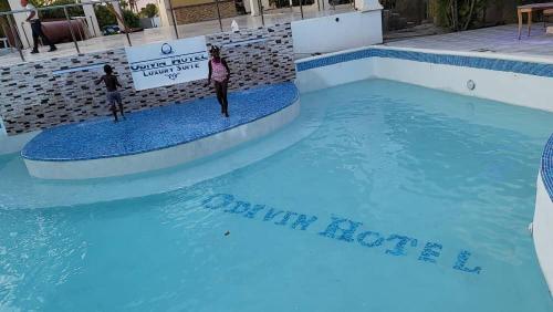 odivin hotel luxury suite في Gonaïves: مسبح من الماء الازرق يقف فيه شخصان