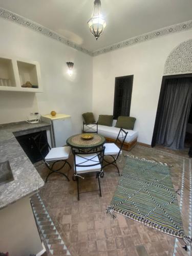 sala de estar con mesa, sillas y chimenea en Dar Fangui, en Marrakech