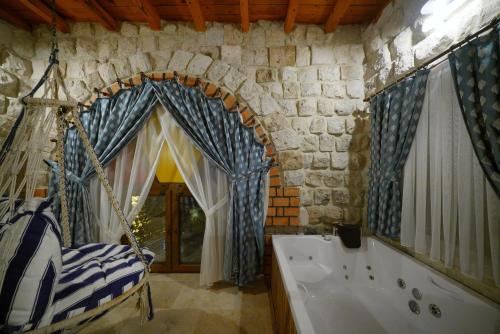 a bathroom with a tub and a swing in a room at Cappadocia Nar Cave House & Swimming Pool in Nevsehir