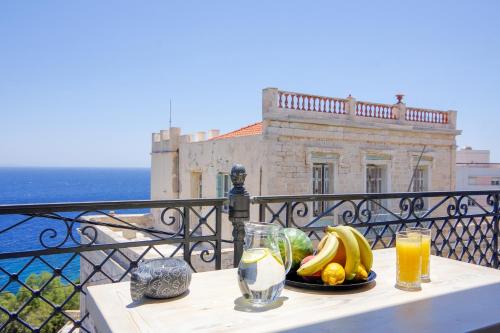 a table with a plate of fruit and drinks on a balcony at Lydia in Ermoupoli