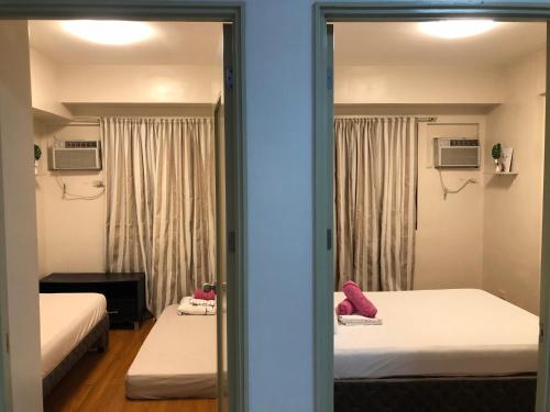 a reflection of a bedroom with two beds and a mirror at Darling Vacation Rental Davao City in Davao City