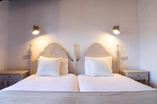 a bedroom with a bed with white sheets and two pillows at Casa rural la grande in Casas del Castañar