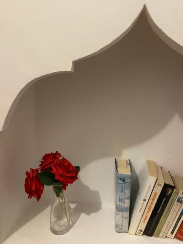 un jarrón con una rosa roja y libros en un estante en Dar Fangui, en Marrakech