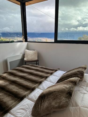 a bed with fur pillows in a room with a window at Les 100 Ciels Font-Romeu in Font Romeu Odeillo Via