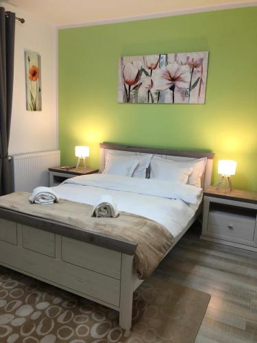 a bedroom with a large bed with two tables and two lamps at Maya Green Residence **** in Sibiu