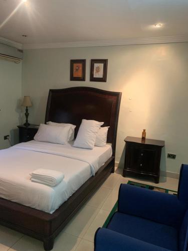 a bedroom with a bed and a blue chair at Tivoli Residence & Hotels in Lagos