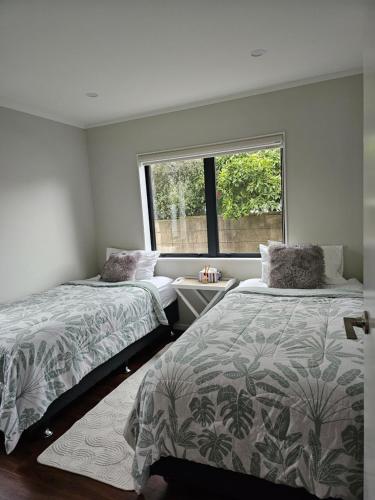 een slaapkamer met 2 bedden en een raam bij Humble Abode in Auckland