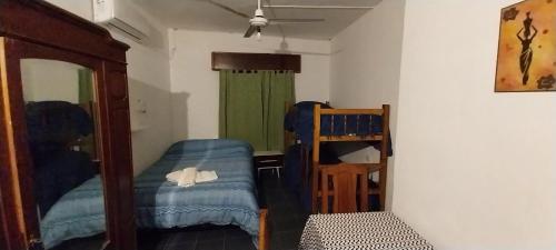 Habitación con cama, silla y espejo. en Hospedaje Maria en Termas de Río Hondo
