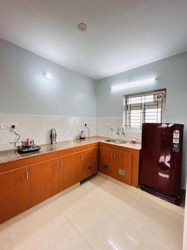 a kitchen with brown cabinets and a black refrigerator at Vishaka Daily Rentals in Tirunelveli