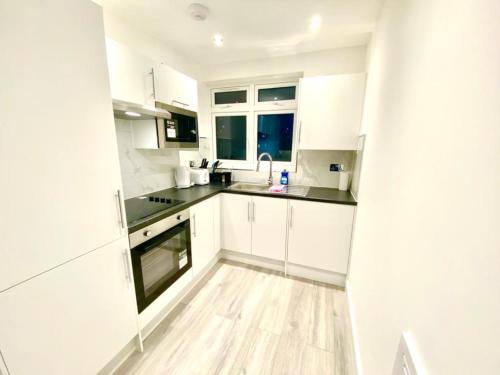 a kitchen with white cabinets and a wooden floor at Lovely One bed apartment In London in London