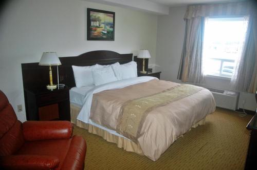 a hotel room with a bed and a chair at Days Inn by Wyndham Athabasca in Athabasca