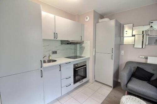 een keuken met witte kasten, een wastafel en een stoel bij La paix à 4 minutes du métro ! in Villejuif