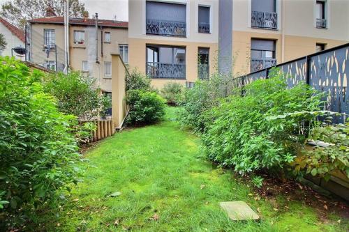 een tuin met gras voor een gebouw bij La paix à 4 minutes du métro ! in Villejuif