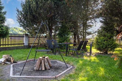 a fire pit in a yard with a table and chairs at Gorczański Zakątek in Konina