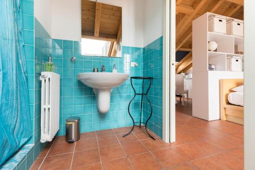 baño con lavabo y azulejos azules en Mortara Navigli Apartments, en Milán