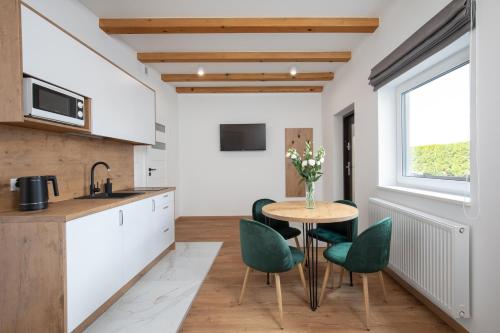 a kitchen with a table and green chairs at Gorczański Zakątek in Konina