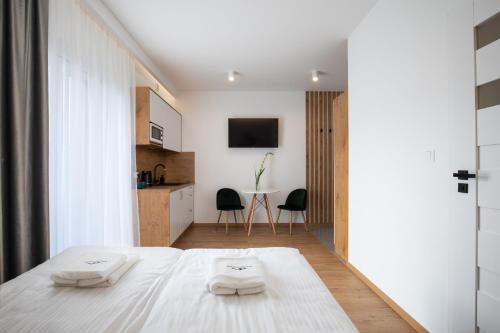 a bedroom with a white bed and a kitchen at Gorczański Zakątek in Konina