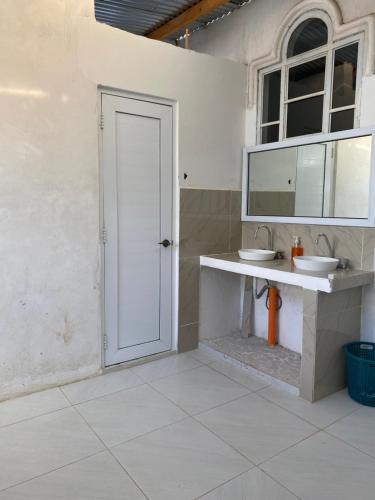 a white bathroom with a sink and a mirror at Casa Elenita in San Juan La Laguna