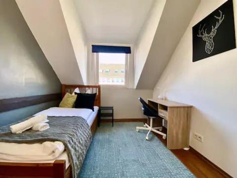 1 dormitorio con cama, escritorio y ventana en Stylische Privatzimmer an der Mosel, en Coblenza