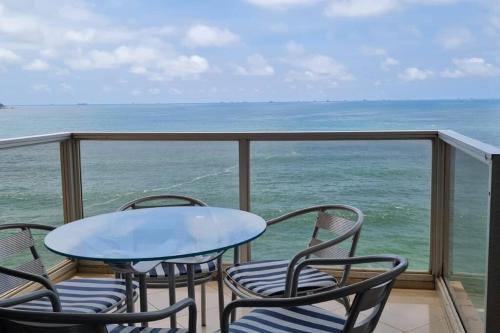 d'une table et de chaises sur un balcon donnant sur l'océan. dans l'établissement Apto Pitangueiras vista para o Mar, à Guarujá