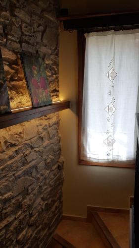 a window with a white curtain and a stone wall at Casa Ton del Mingo in Sant Cerni