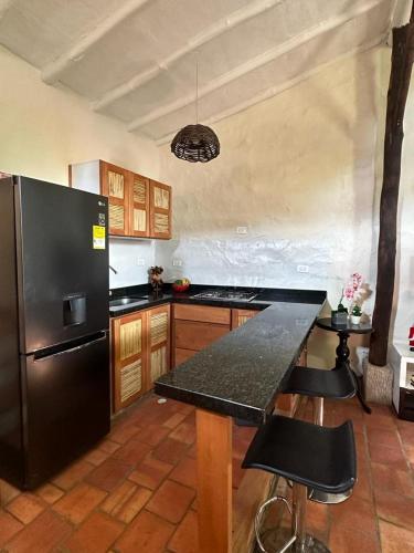 a kitchen with a black refrigerator and a table at Hospedaje La Casita de Maria in Barichara