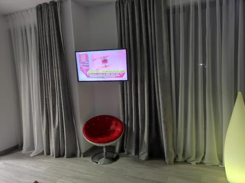 a room with a red chair and a television at Regal Guest House in Sighetu Marmaţiei