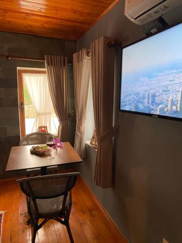 um quarto com uma mesa e uma grande televisão na parede em Keshtjella Xhabeqos em Tirana