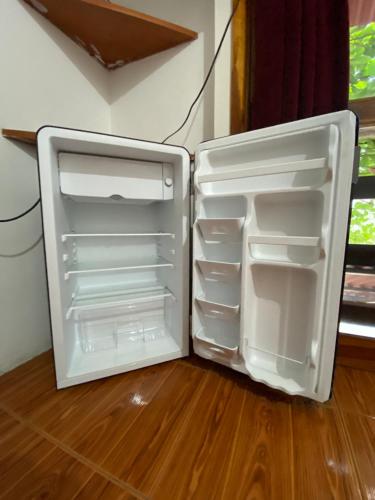 a white refrigerator with its door open on a wooden floor at UFO House in Montañita