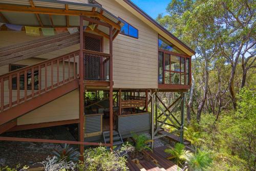 a tree house with a deck in the woods at Sandalwood in Dunbogan