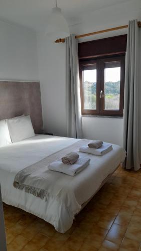 a bedroom with a large bed with towels on it at Na Rota - Casa de Praia in Zambujeira do Mar