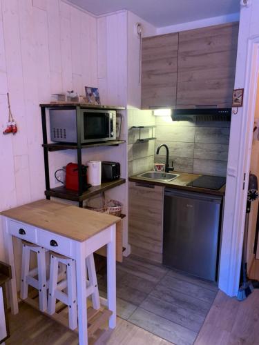 une petite cuisine avec une table et un micro-ondes dans l'établissement Studio 5 couchages SCHUSS 5 la foux d’allos, à Allos