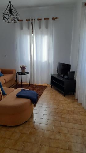 un soggiorno con divano e TV a schermo piatto di Na Rota - Casa de Praia a Zambujeira do Mar