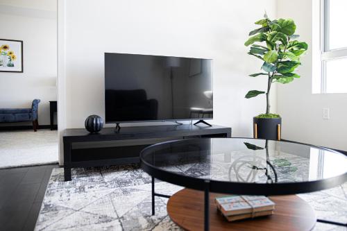 洛杉磯的住宿－One Bedroom Gem In Weho，客厅配有玻璃桌和电视