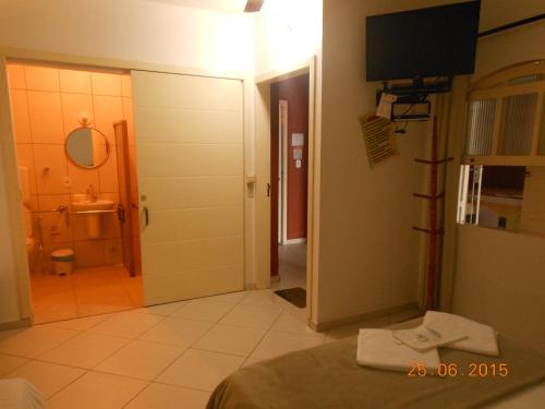 a room with a bathroom with a toilet and a television at Pousada Xodó da Praia in São Pedro da Aldeia