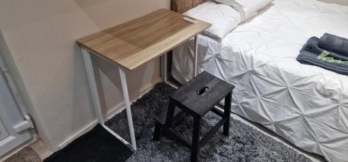 uma pequena mesa de madeira ao lado de uma cama em Oleon Apartments - Colchester em Colchester