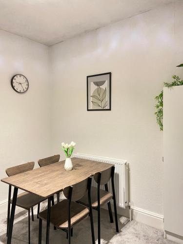 Una mesa de comedor con sillas y un reloj en la pared. en Kisobi Home Bedroom 1, en Hull