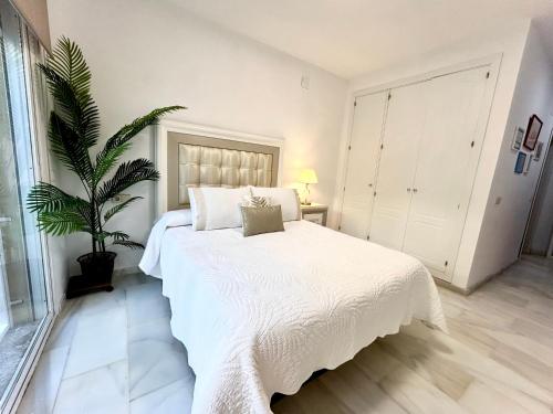 1 dormitorio con cama blanca y maceta en Casa Caracol, en La Herradura