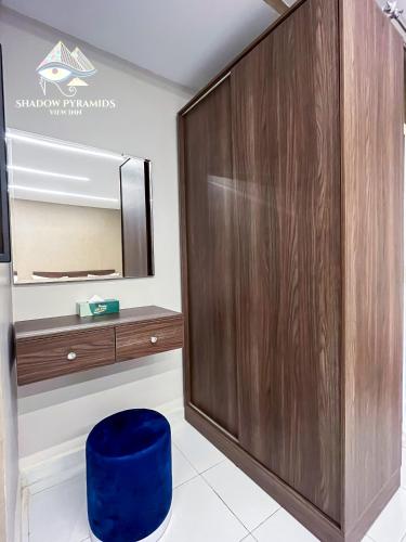 a large wooden wardrobe in a bathroom with a blue stool at Shadow Pyramids Suites and Jacuzzi in Cairo