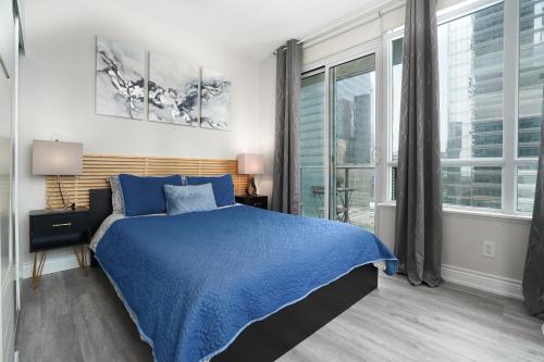 um quarto com uma cama azul e uma grande janela em Simply Comfort Suites - One plus Den Apartment with Scotiabank Arena View em Toronto