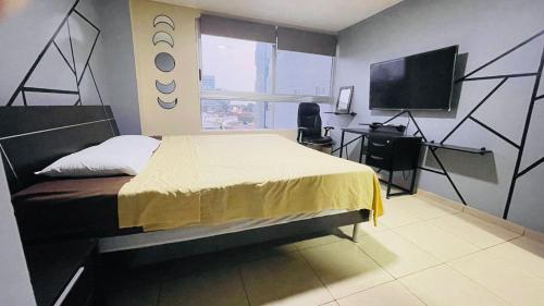 Dormitorio con cama, escritorio y TV en Five Stars Suites - Kennedy - Guayaquil, en Guayaquil
